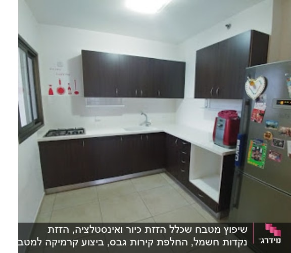 מטבח עם ארונות כהים, מקרר ותמונות על הקיר